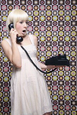 Woman looking shocked while talking on the phoneの写真素材