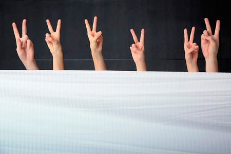 Hands showing various gestures behind comforter