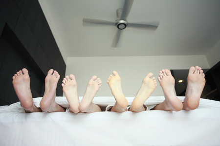 Feet sticking out from under comforter on bedの写真素材