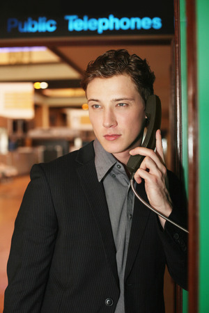 Businessman using public telephone at the airport