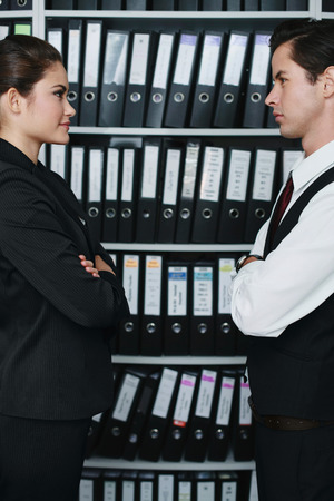 Businessman and businesswoman with their arms crossed, looking at each otherの写真素材