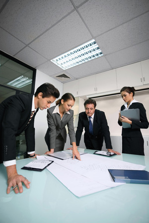 Business people reviewing blueprints togetherの写真素材