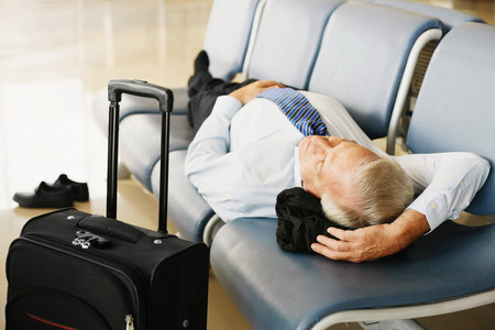 Businessman asleep on seat in airport loungeの写真素材