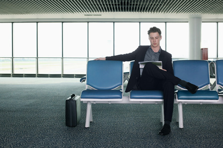 Businessman reading newspaper in airport loungeの写真素材