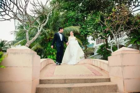 Bride and groom walking together on a bridgeの写真素材
