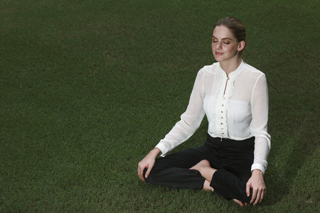 Businesswoman meditating on the fieldの写真素材