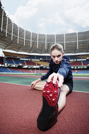 Female athlete warming up on running trackの写真素材
