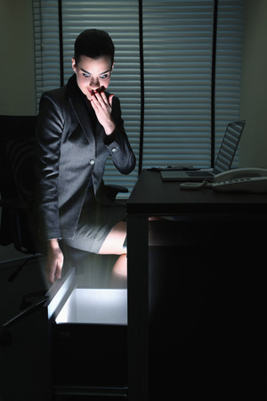 Businesswoman looking into a glowing drawerの写真素材
