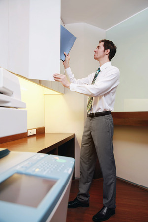 Businessman placing folder in filing cabinet