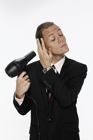 Businessman blowing hair with hairdryerの写真素材