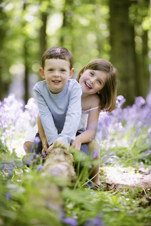 Boy and girl sitting on tree rootの写真素材