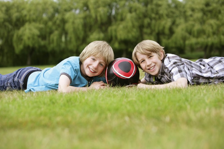 Boys lying on grass with soccer ballの写真素材