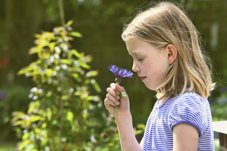 Girl smelling a flower with eyes closedの写真素材
