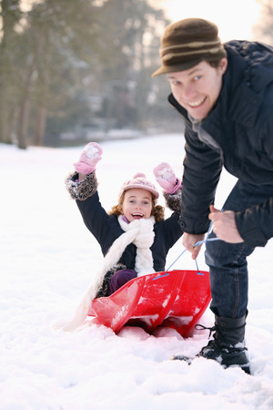 Father playing with daughter in the snowの写真素材