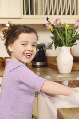 Girl playing with bubbles in the kitchen sinkの写真素材