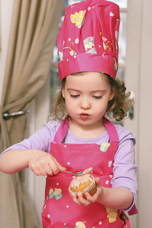 Girl spreading icing on cupcakeの写真素材