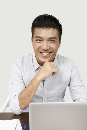 Businessman smiling at the camera while working on his laptopの写真素材