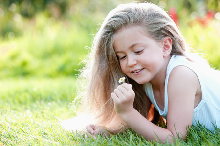 Girl holding a small daisyの写真素材