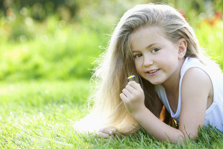 Girl holding a small daisyの写真素材