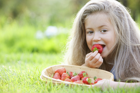 Girl eating a strawberryの写真素材