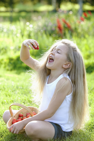 Girl eating a strawberryの写真素材