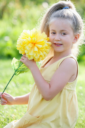 Girl holding a big yellow flowerの写真素材