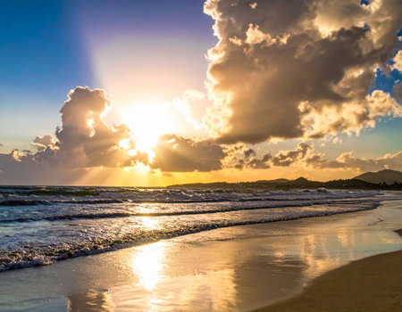 Tropical beach at sunset with sunbeams shining through cloudsの素材
