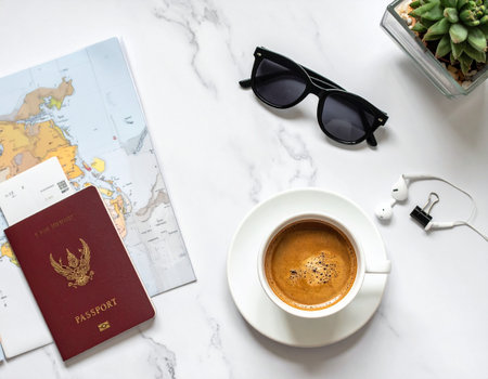 Travel planning concept with passport, coffee and glasses on white marble backgroundの素材