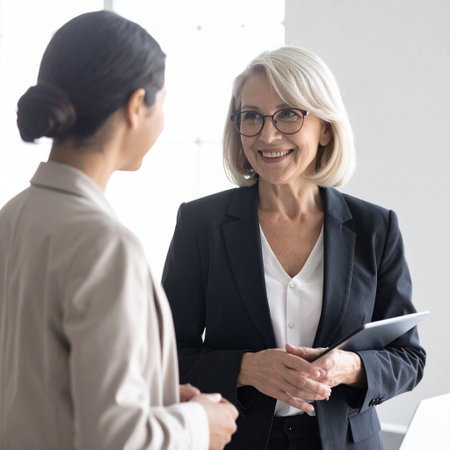 Smiling mature businesswoman talking to her colleague in office, copy spaceの素材