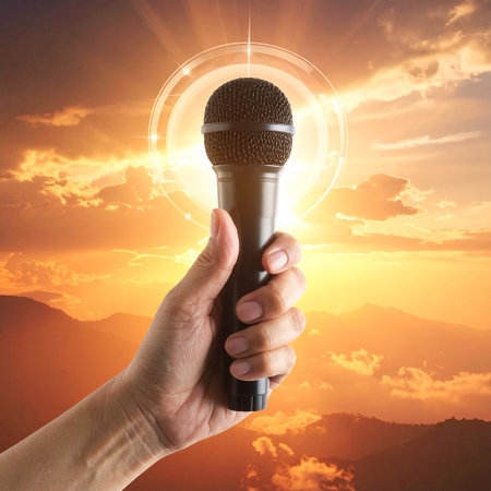 Female hand holding a microphone on a background of mountains and sunset.の素材