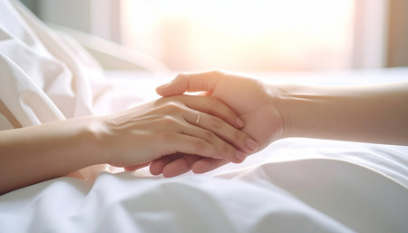 Hands of man and woman holding hands on bed in bedroom.の素材