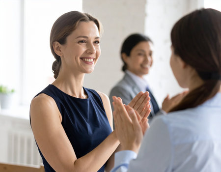 Smiling young businesswoman giving high five to colleague in office. Happy businesswoman giving high five to colleague, congratulating with good deal or success. Success conceptの素材