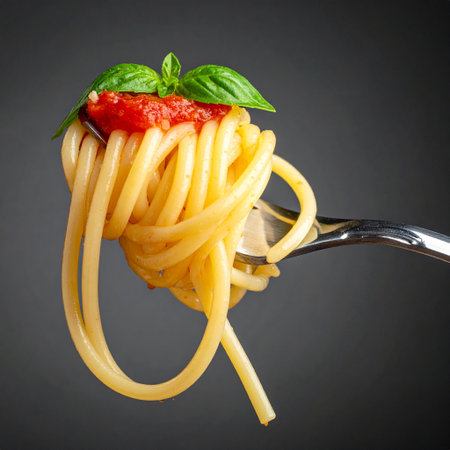 Spaghetti with tomato sauce and basil on a fork on a dark backgroundの素材