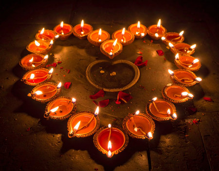 Burning diya in shape of heart on dark background for Diwali festivalの素材