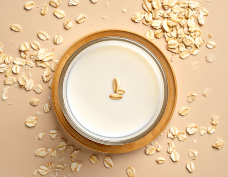 Oat milk in a glass jar and oatmeal on a beige backgroundの素材