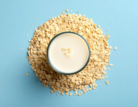Glass of oat milk and oatmeal on blue background, top viewの素材