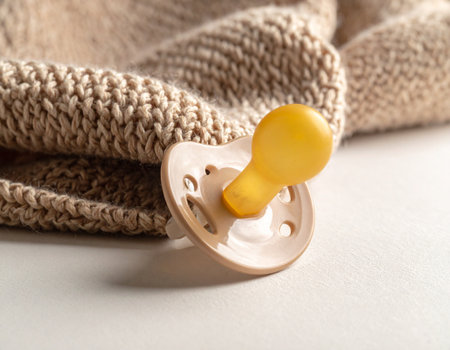 Baby pacifier and knitted scarf on white background, closeupの素材