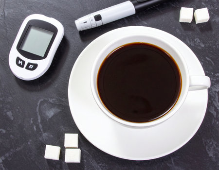 Cup of coffee with sugar and glucometer on tableの素材