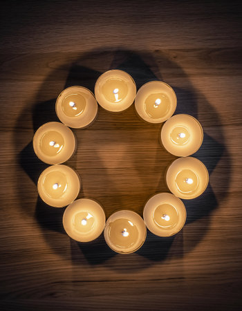 Burning candles in the shape of a circle on a wooden backgroundの素材
