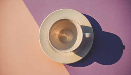 Cup of coffee on purple and pink background with hard shadow.の素材