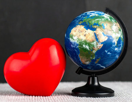 Globe and red heart on a black background. Save the planet concept.の素材