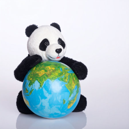 Panda sitting with a globe on a white background, isolated.の素材