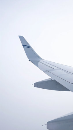 Wing of an airplane flying in the blue sky, closeup of photoの素材