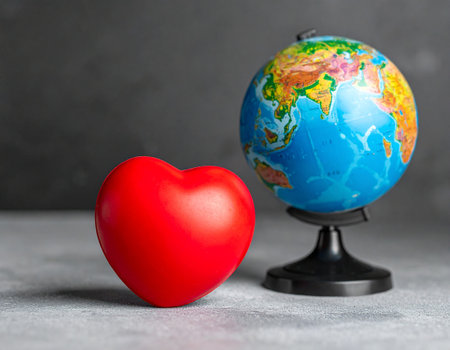 Red heart and globe on grey background. Valentine's day concept.の素材