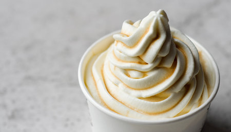 Vanilla frozen yogurt with whipped cream in a white cup on a light backgroundの素材