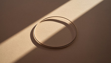 Round gold podium on a beige background with a shadow from the sunの素材