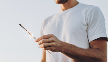 Cropped image of young man holding sparkler on the beach.の素材