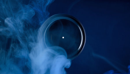 Camera lens with smoke on a dark blue background. Close-upの素材