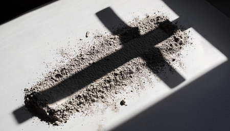 Black cross made of sand on a white plate. Shadow from the cross.の素材