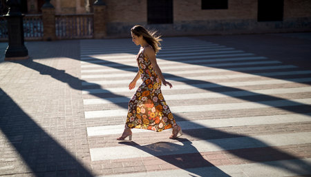 Beautiful woman in a long dress walking in the street in Spainの素材